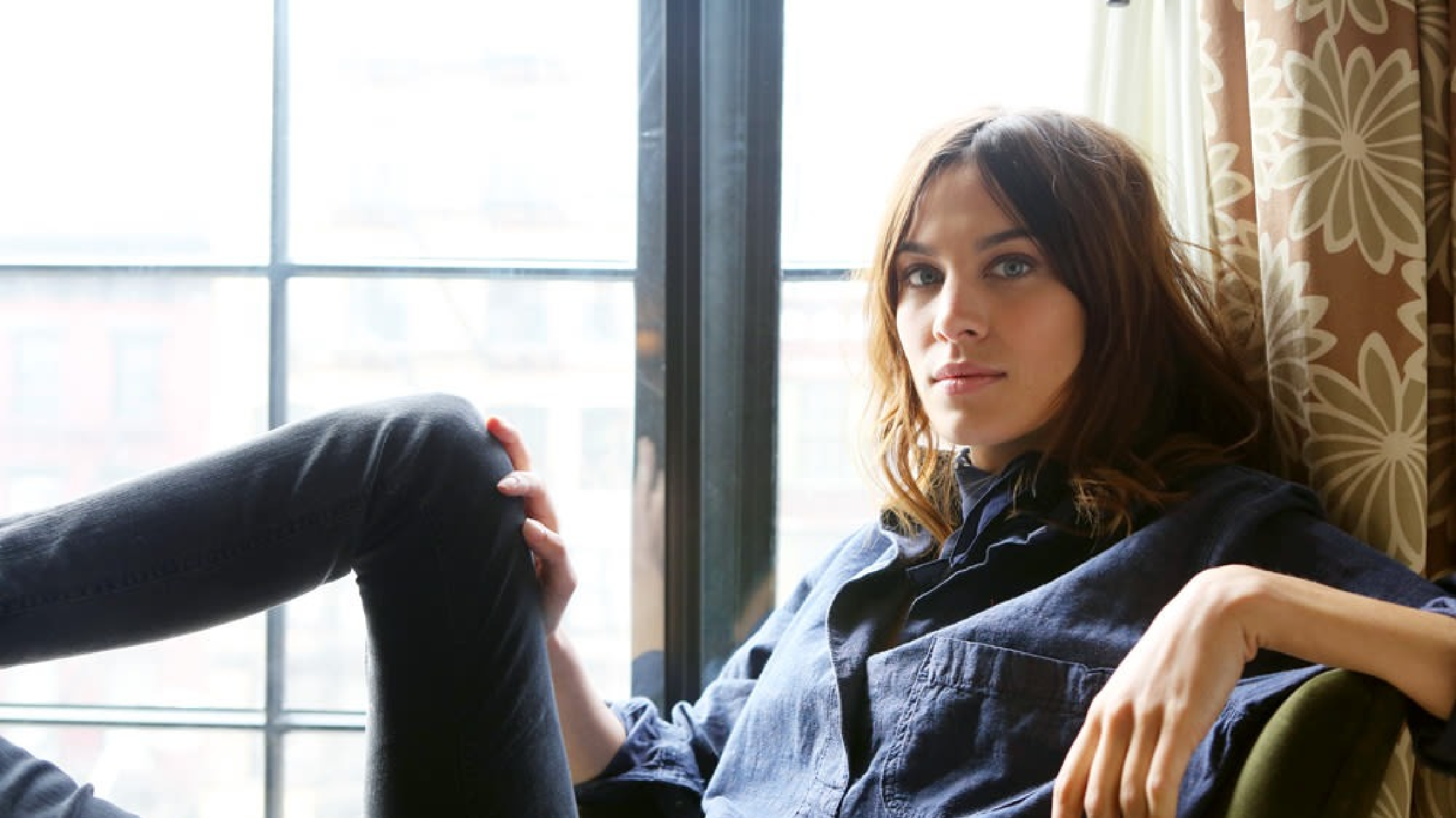 Alexa Chung walking in Mayfair during London Fashion Week 2026, wearing a single-breasted, sand beige trench coat with a straight, relaxed silhouette, pointed collar, and concealed buttons, styled over casual citywear in a chic minimalist London street setting.
