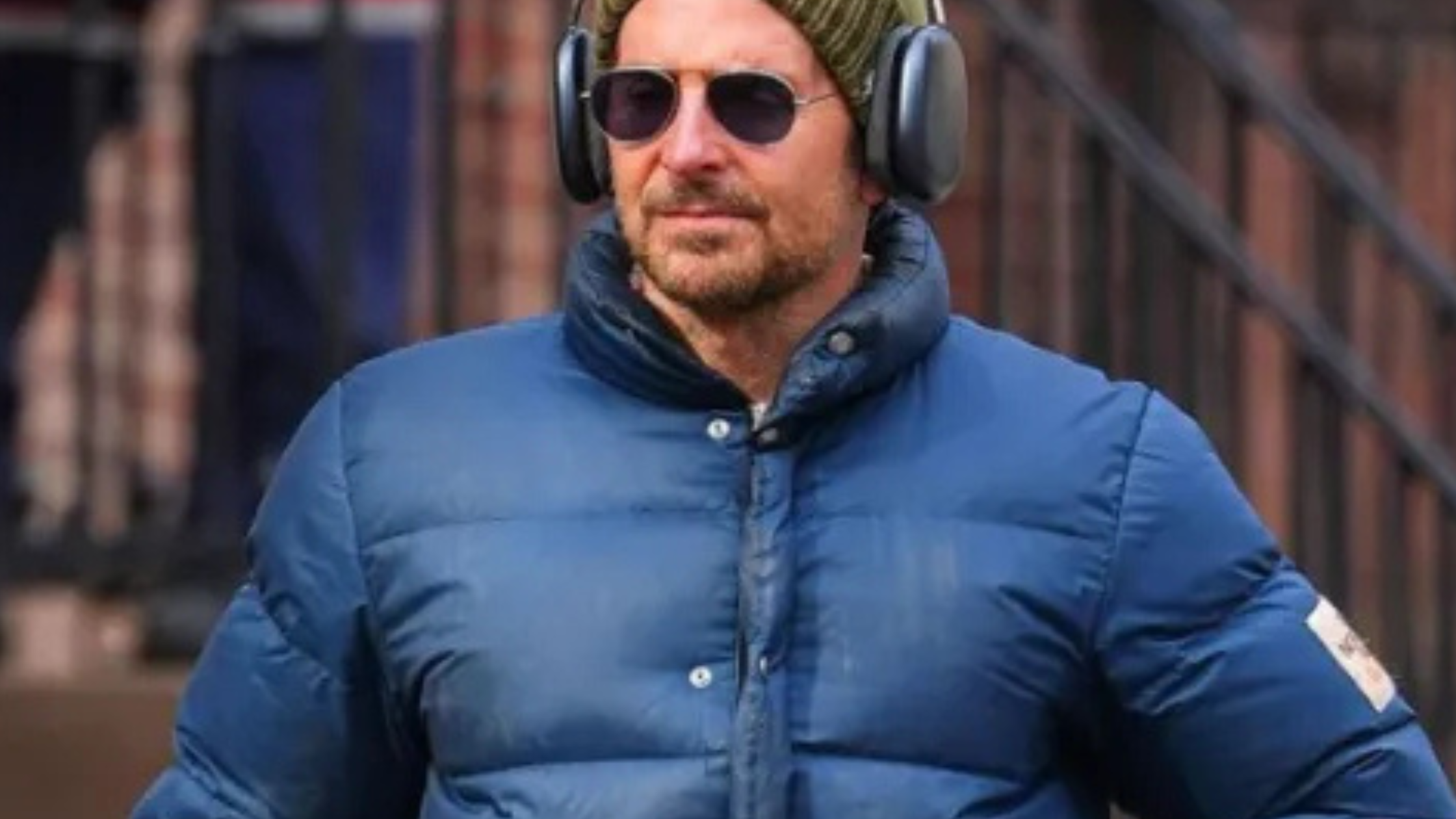 Bradley Cooper wearing a navy blue quilted puffer jacket with funnel collar and oversized pockets during a winter street style moment in New York City.