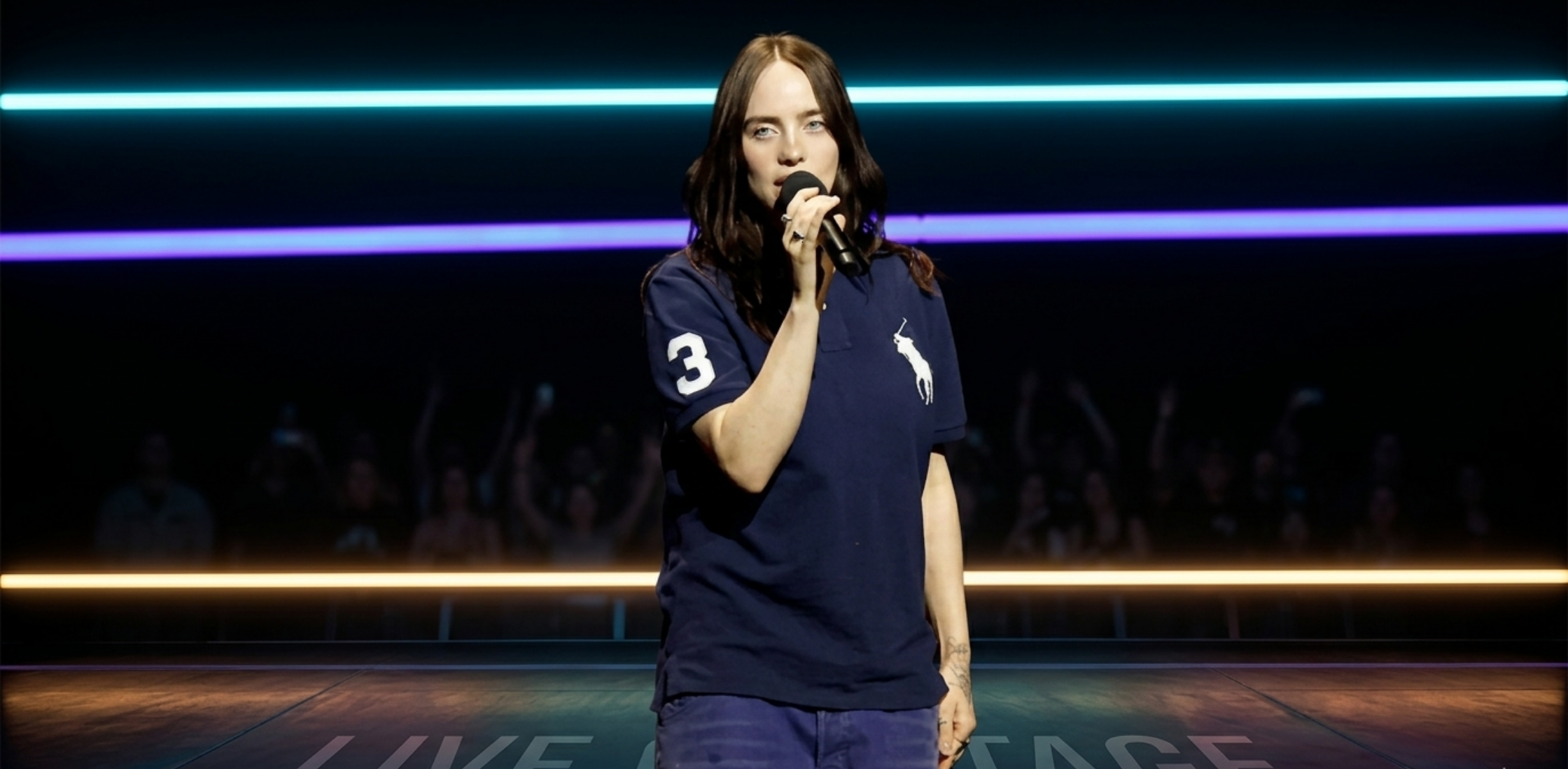Billie Eilish CinemaCon 2026 blue navy polo shirt with white embroidered logo and sleeve number detail