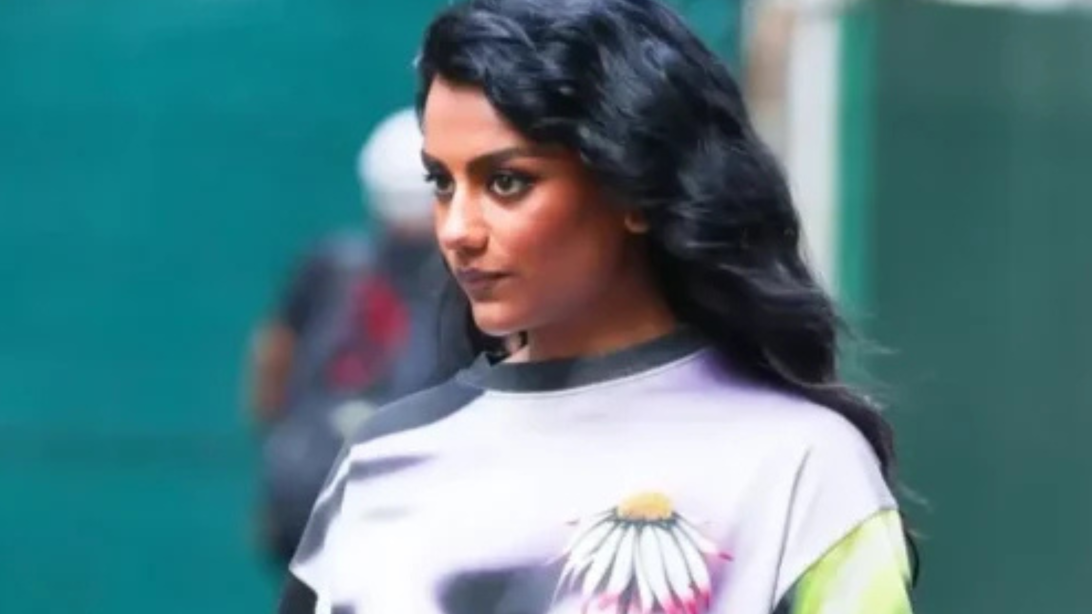 Simone Ashley wearing a multicolor sweatshirt with neon gradient sleeves and floral graphic in New York City, showcasing bold artistic streetwear style