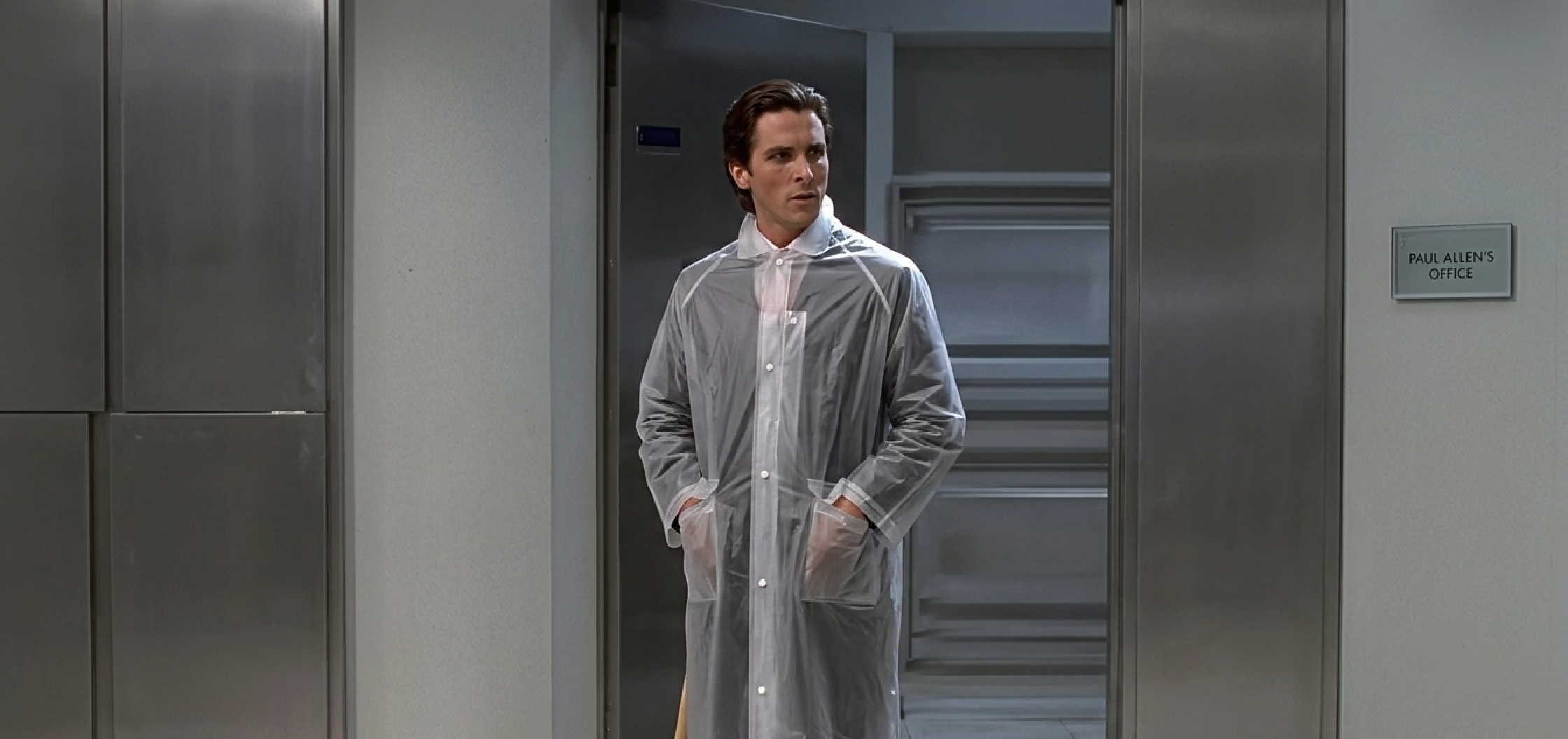 Transparent minimalist Patrick Bateman-inspired PVC raincoat with white piping, club collar, snap closure, and oversized pockets revealing tailored suit underneath