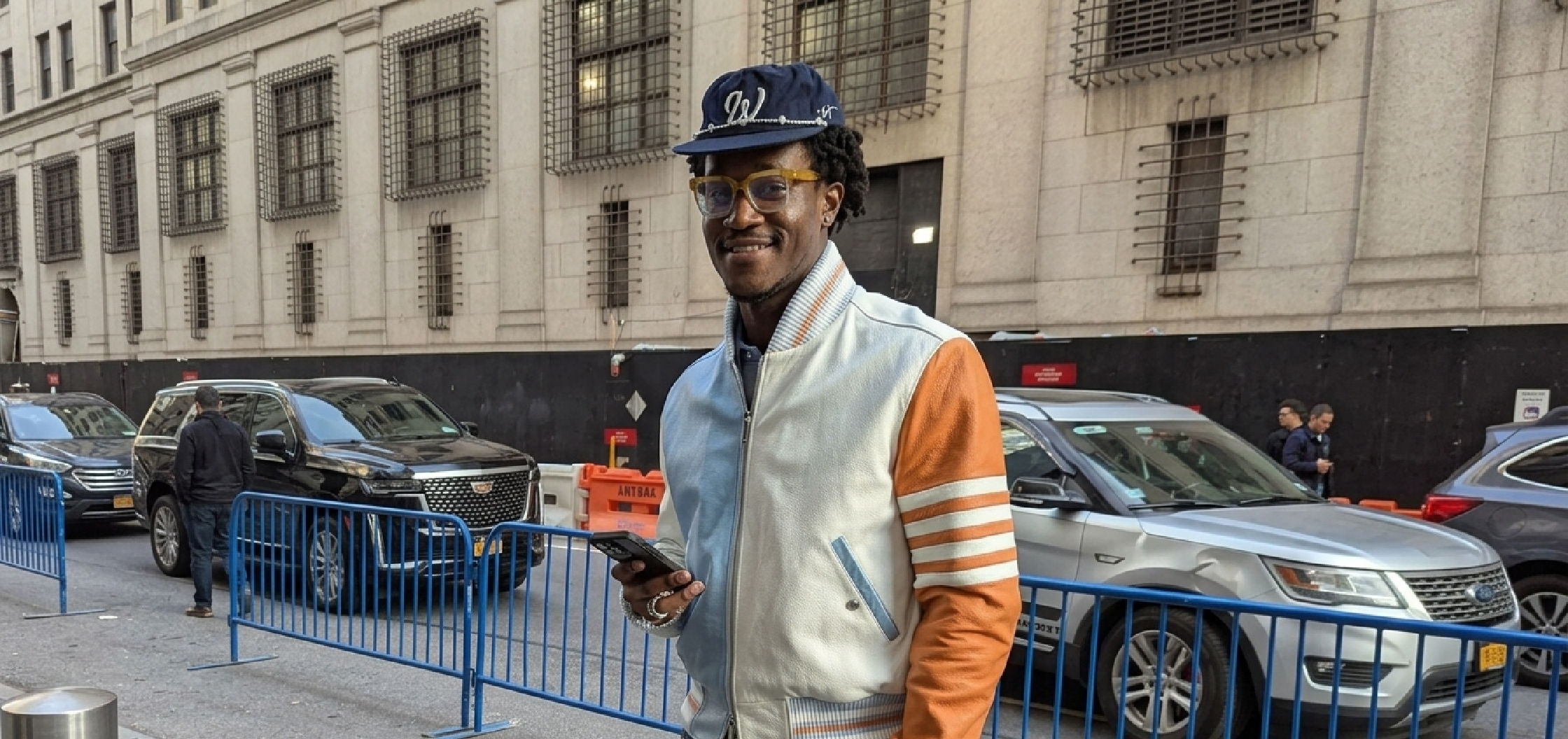 Wisdom Kaye New York City 2026 4-Bar Stripe asymmetrical color block leather varsity bomber jacket featuring pastel blue and burnt orange panels, white torso, 4-bar sleeve stripes, ribbed cuffs, and silver zipper.