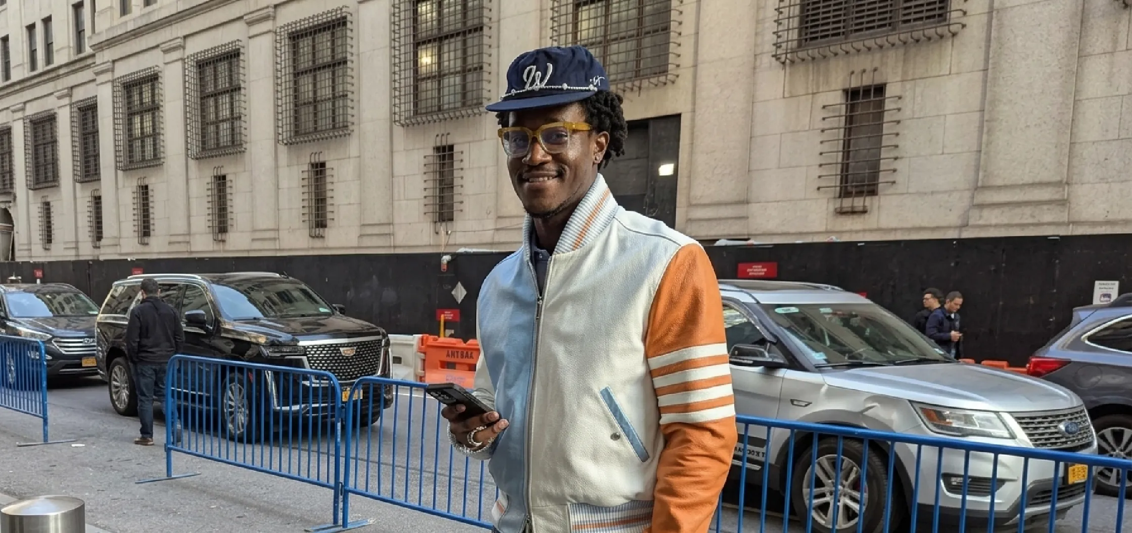 Wisdom Kaye New York City 2026 4-Bar Stripe asymmetrical color block leather varsity bomber jacket featuring pastel blue and burnt orange panels, white torso, 4-bar sleeve stripes, ribbed cuffs, and silver zipper.