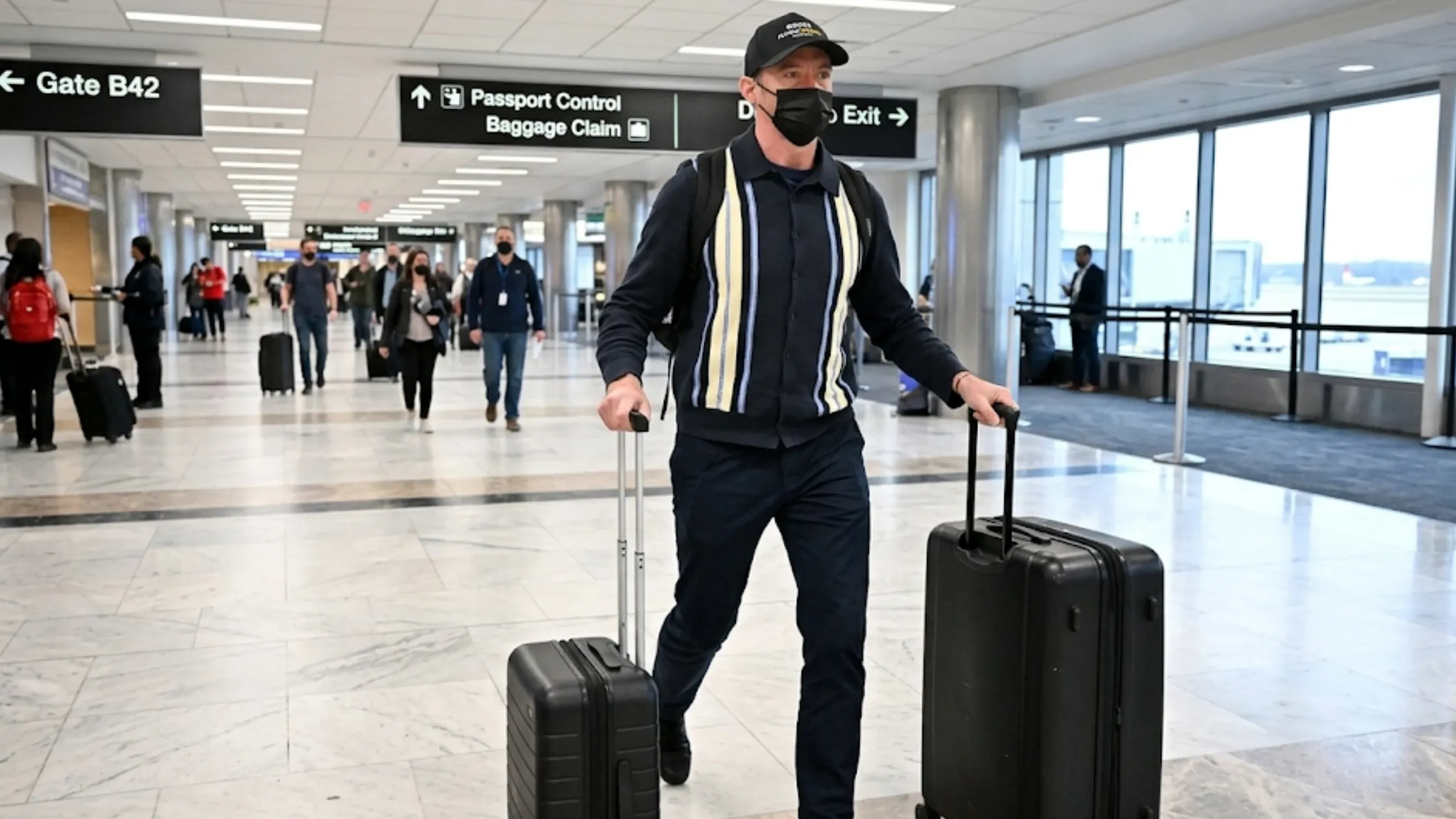 Hugh Jackman NYC 2026 structured polo collar black cardigan with vertical cream stripe panels and full button closure travel outfit