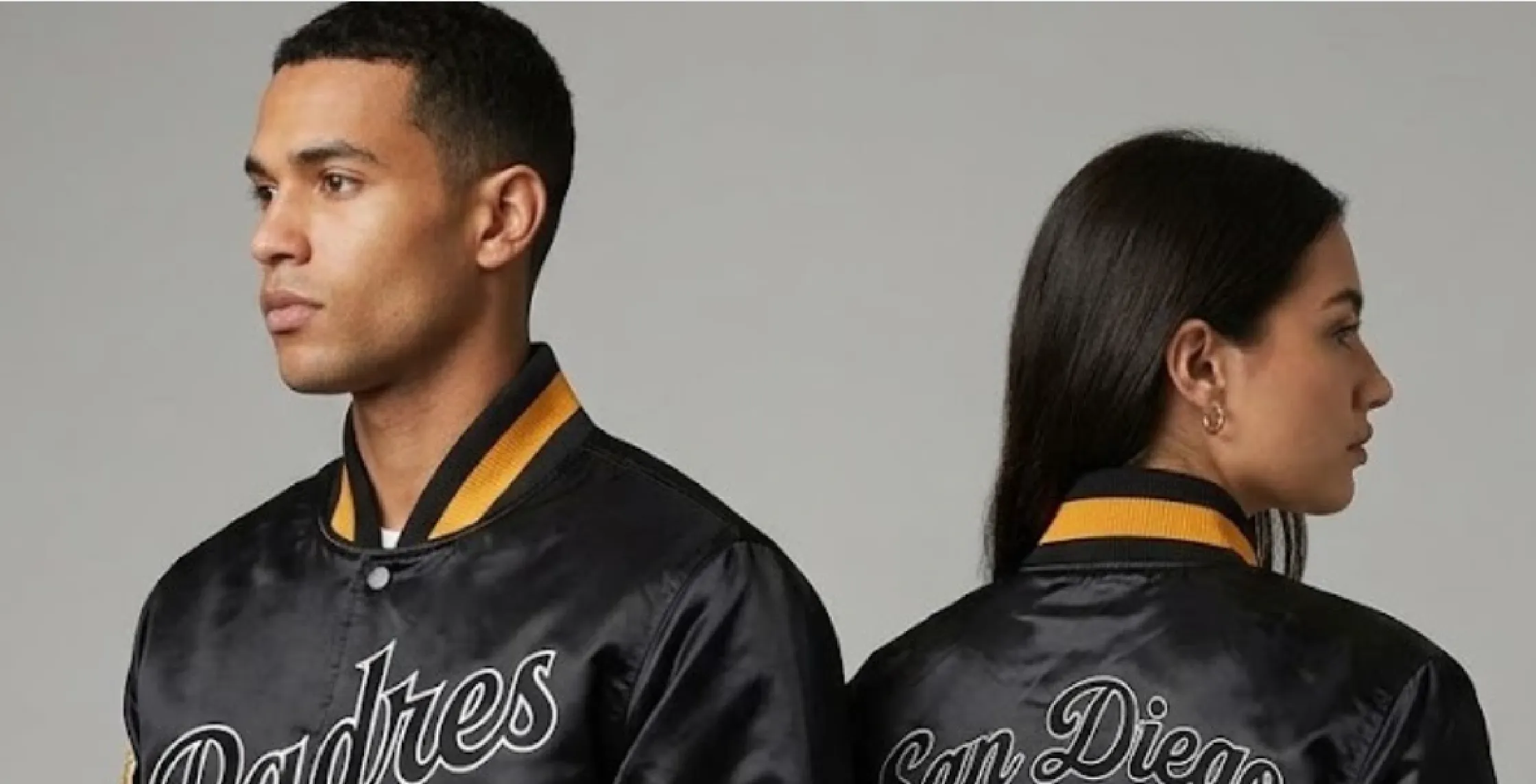 San Diego Padres exclusive black satin bomber jacket with SD logo, striped rib-knit trim, sleeve patches, and orange accents styled for streetwear and game day fashion