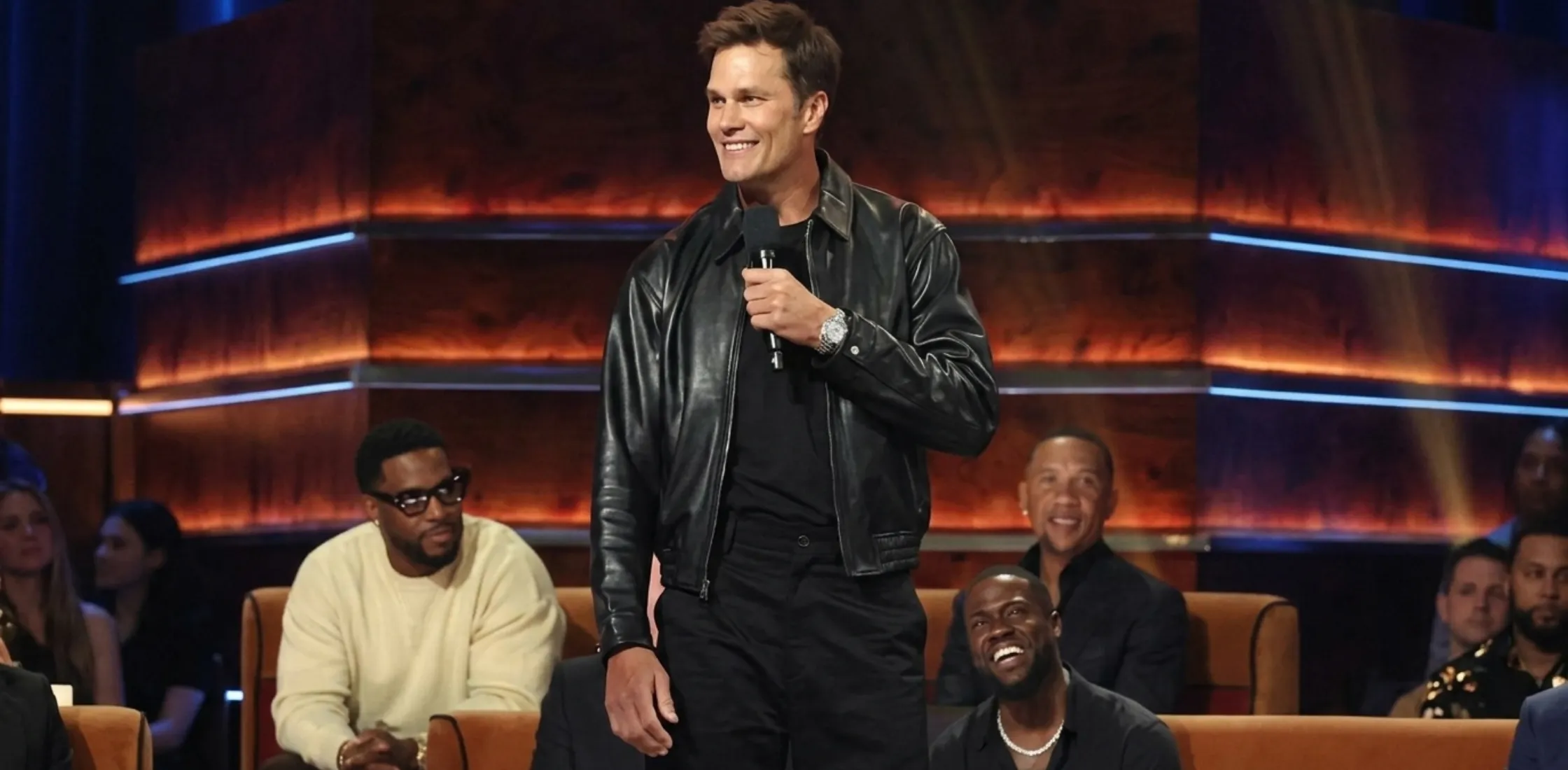 Tom Brady wearing a black leather jacket at Netflix Is A Joke Festival Presents: The Roast of Kevin Hart, showcasing a sleek monochrome celebrity streetwear look with luxury style and modern bomber silhouette.