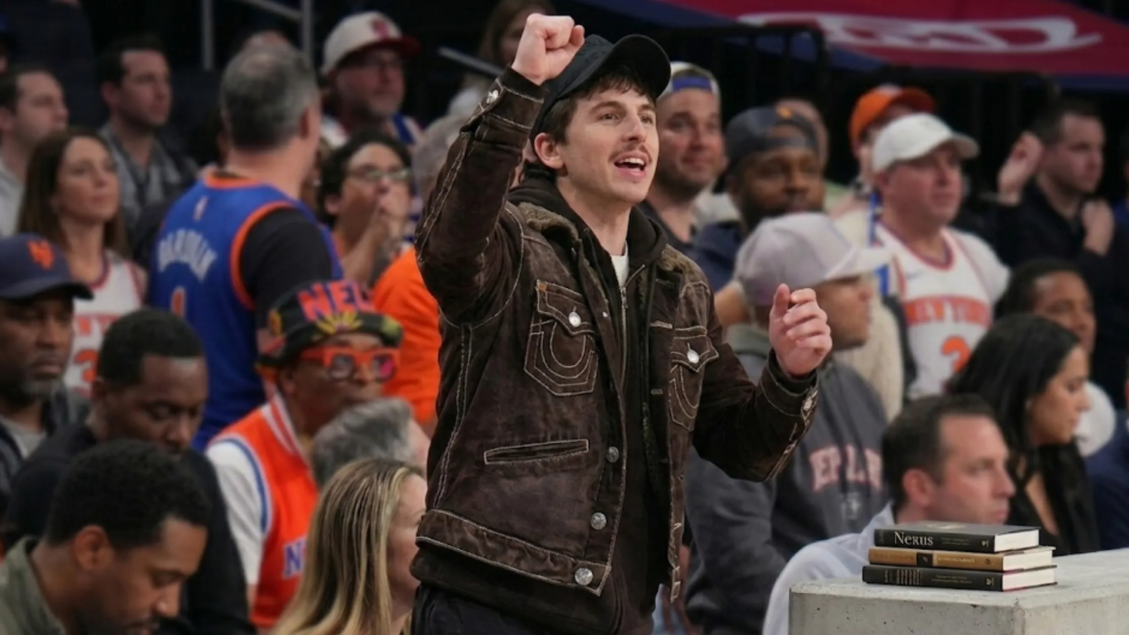 Timothée Chalamet brown corduroy trucker jacket with sherpa collar, contrast stitching, Western yoke, styled for Knicks courtside streetwear look