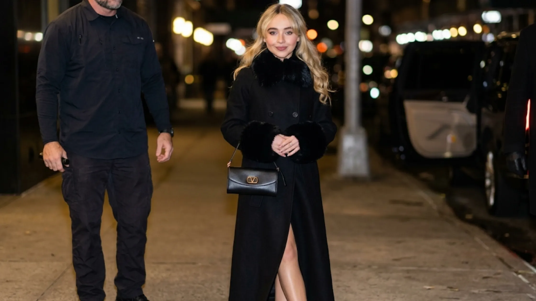 Sabrina Carpenter NYC 2026 black fur trim coat with faux-fur collar, fur cuffs, double-breasted front, and longline silhouette