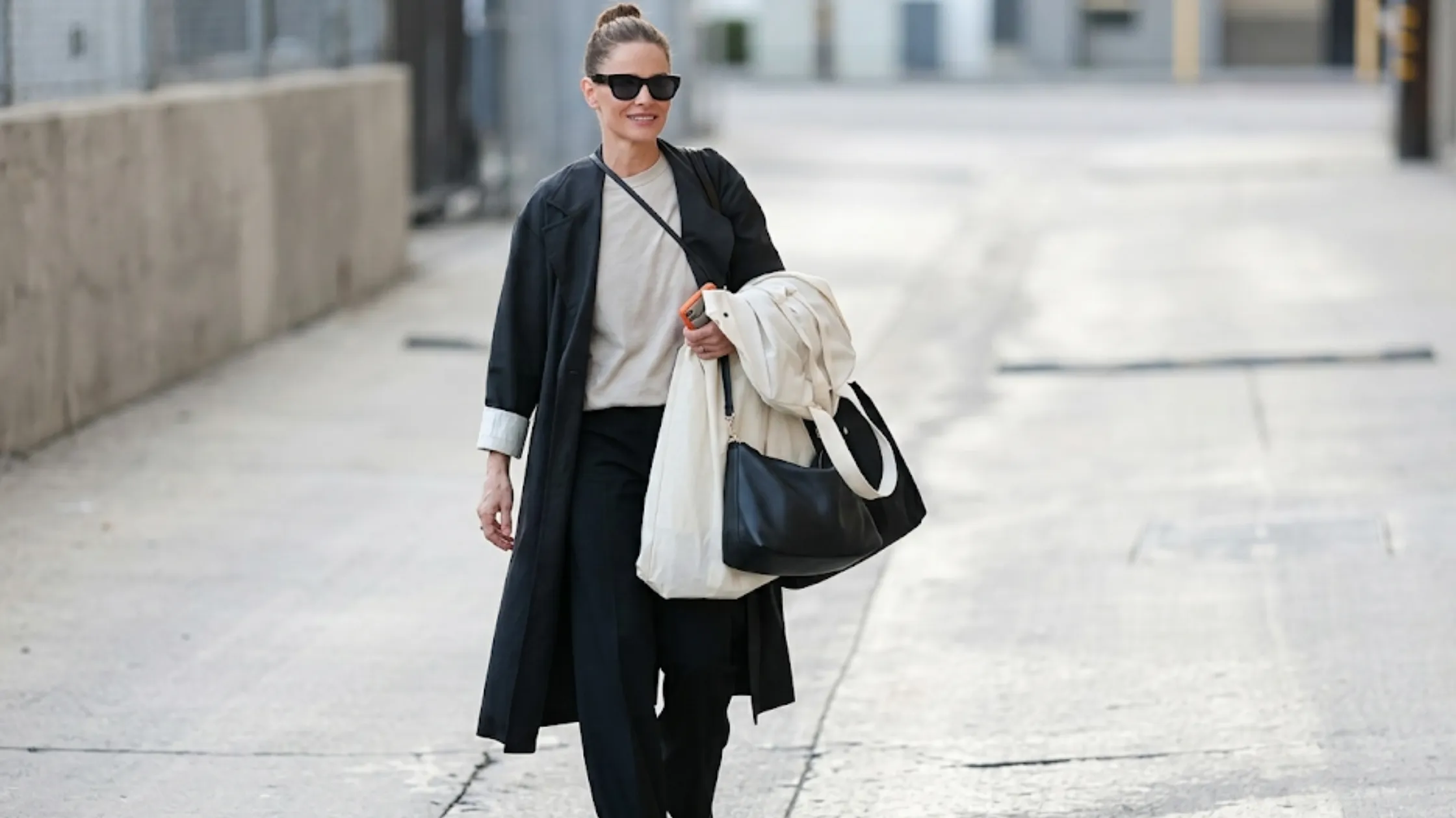 Amanda Peet Los Angeles 2026 washed black longline coat with peak lapel collar and contrasting oversized cuffs