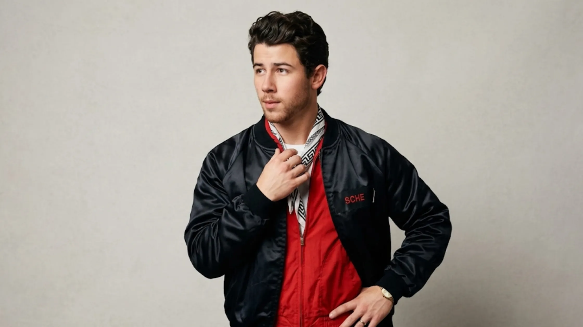 Nick Jonas performing on stage at the Tecate Emblema festival wearing a black satin Porsche motorsport graphic bomber jacket.