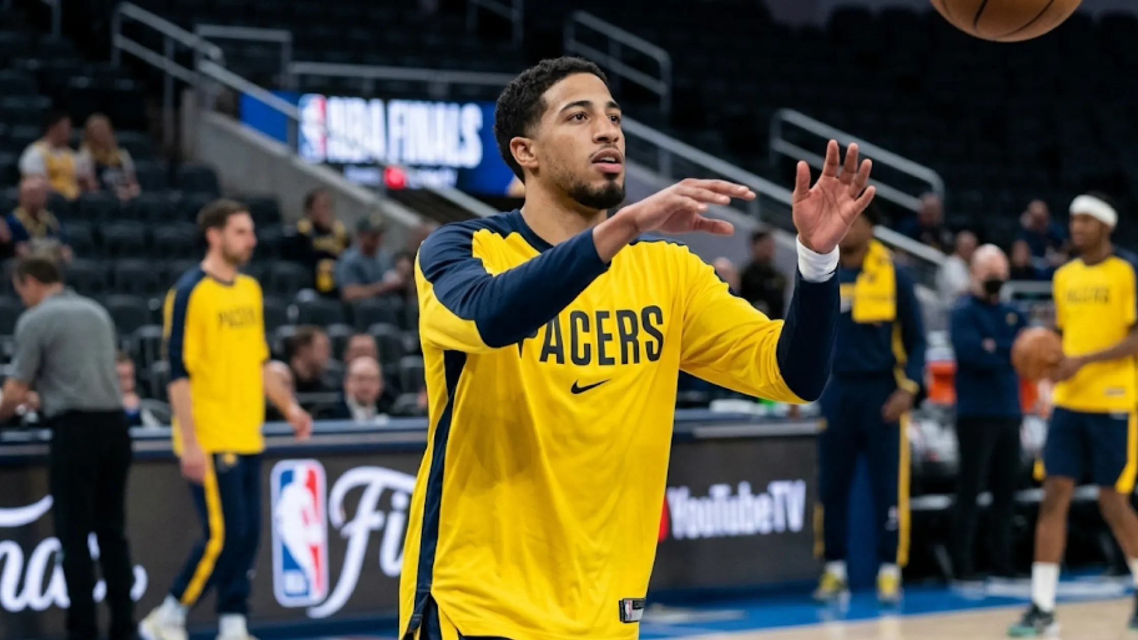 Tyrese Haliburton wearing the gold and navy Indiana Pacers long-sleeve performance shooting shirt during a warmup session on court.