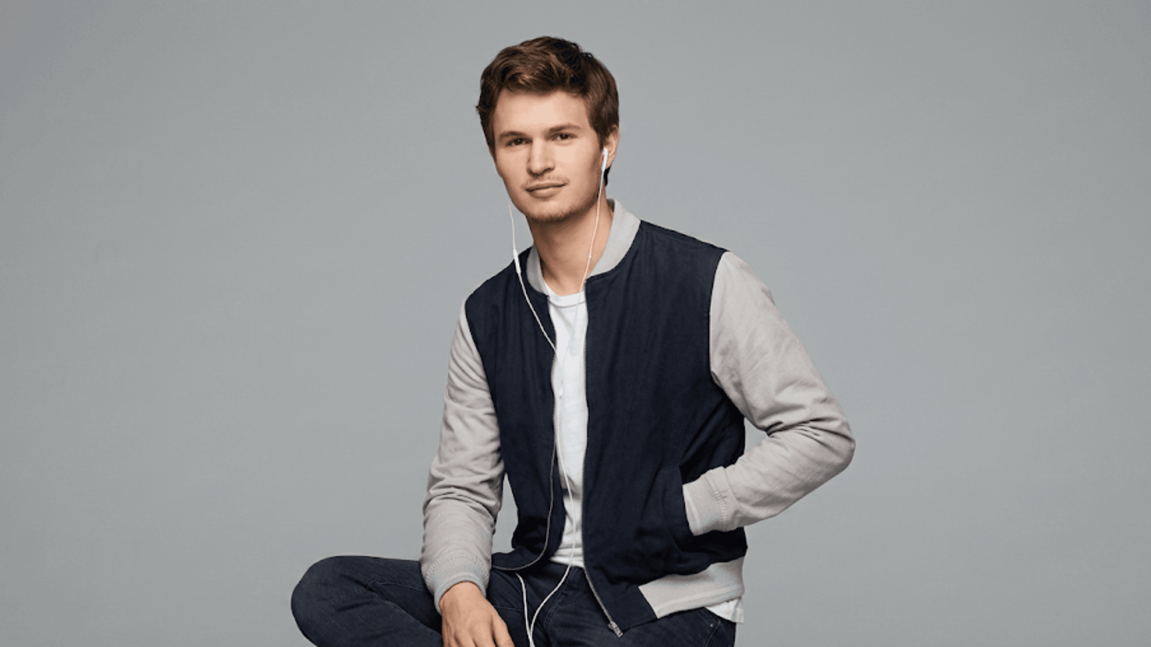 Ansel Elgort as Baby in Baby Driver wearing a black and grey varsity bomber jacket.