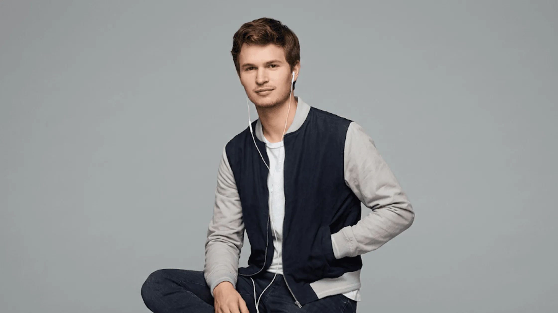 Ansel Elgort as Baby in Baby Driver wearing a black and grey varsity bomber jacket.