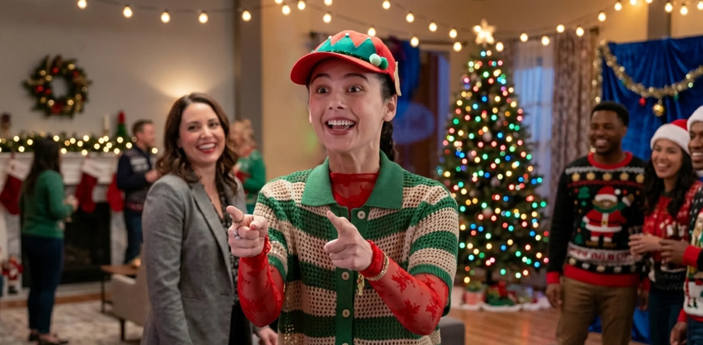 Violet Wilner wearing a green and cream crochet striped short sleeve shirt layered with a red inner top and styled with bold accessories in Mistletoe Murders S02