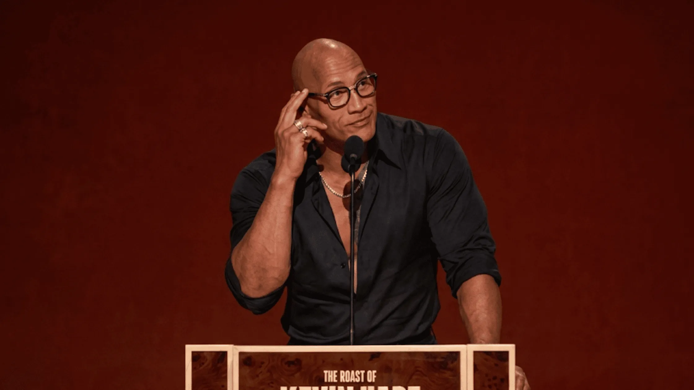 Dwayne Johnson wearing a black dress shirt at the Roast of Kevin Hart blog banner image.