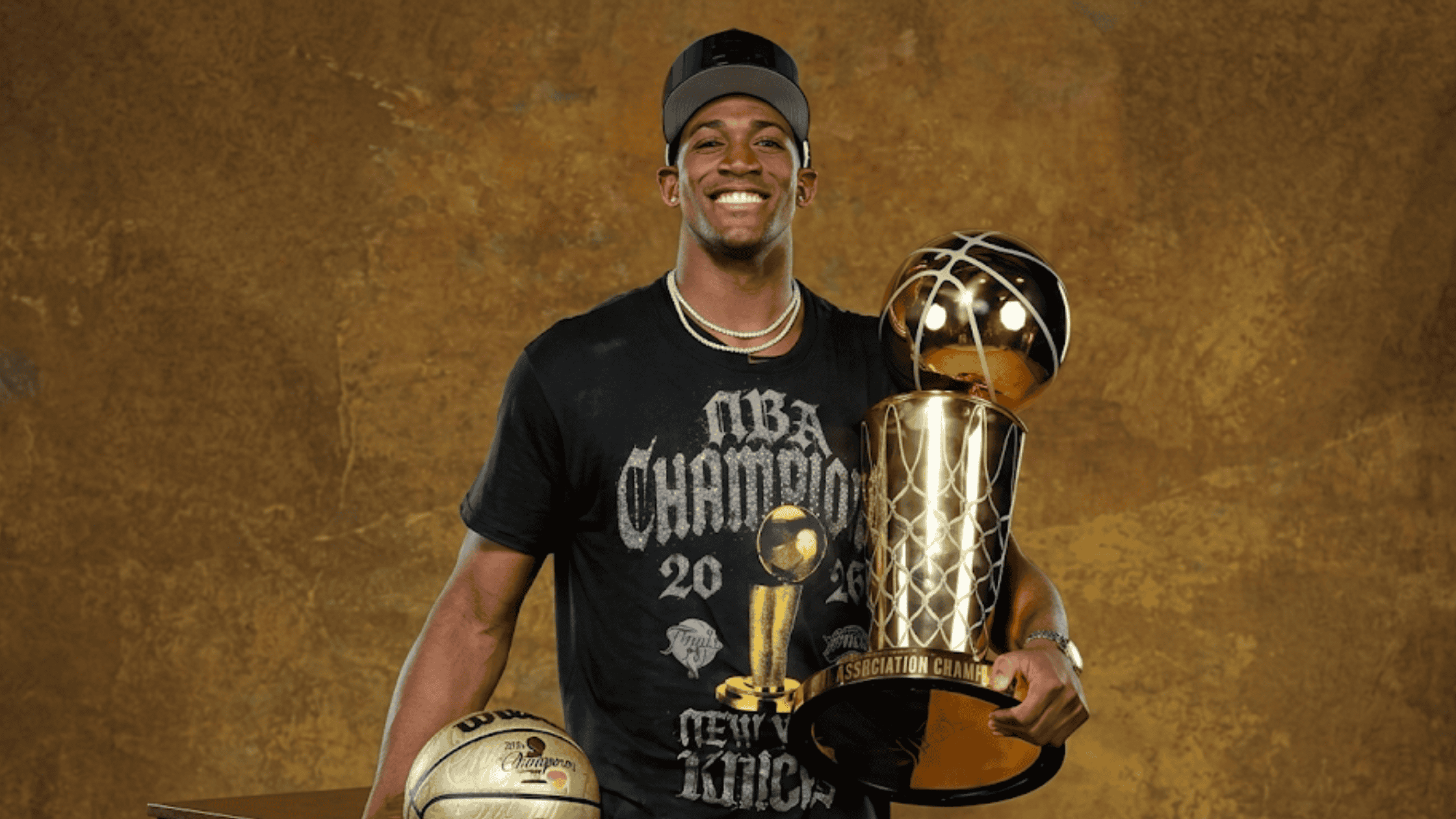 Trey Jemison wearing the New York Knicks 2026 NBA Champions black crewneck t-shirt featuring a metallic gold Larry O'Brien trophy graphic and gothic script.