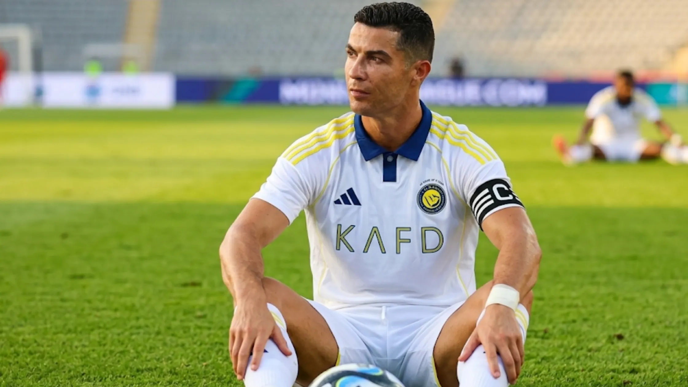 Cristiano Ronaldo Al Nassr FC 2025-26 white soccer jersey with navy collar, yellow shoulder stripes, Al Nassr crest, Adidas logo, and sponsor graphics.
