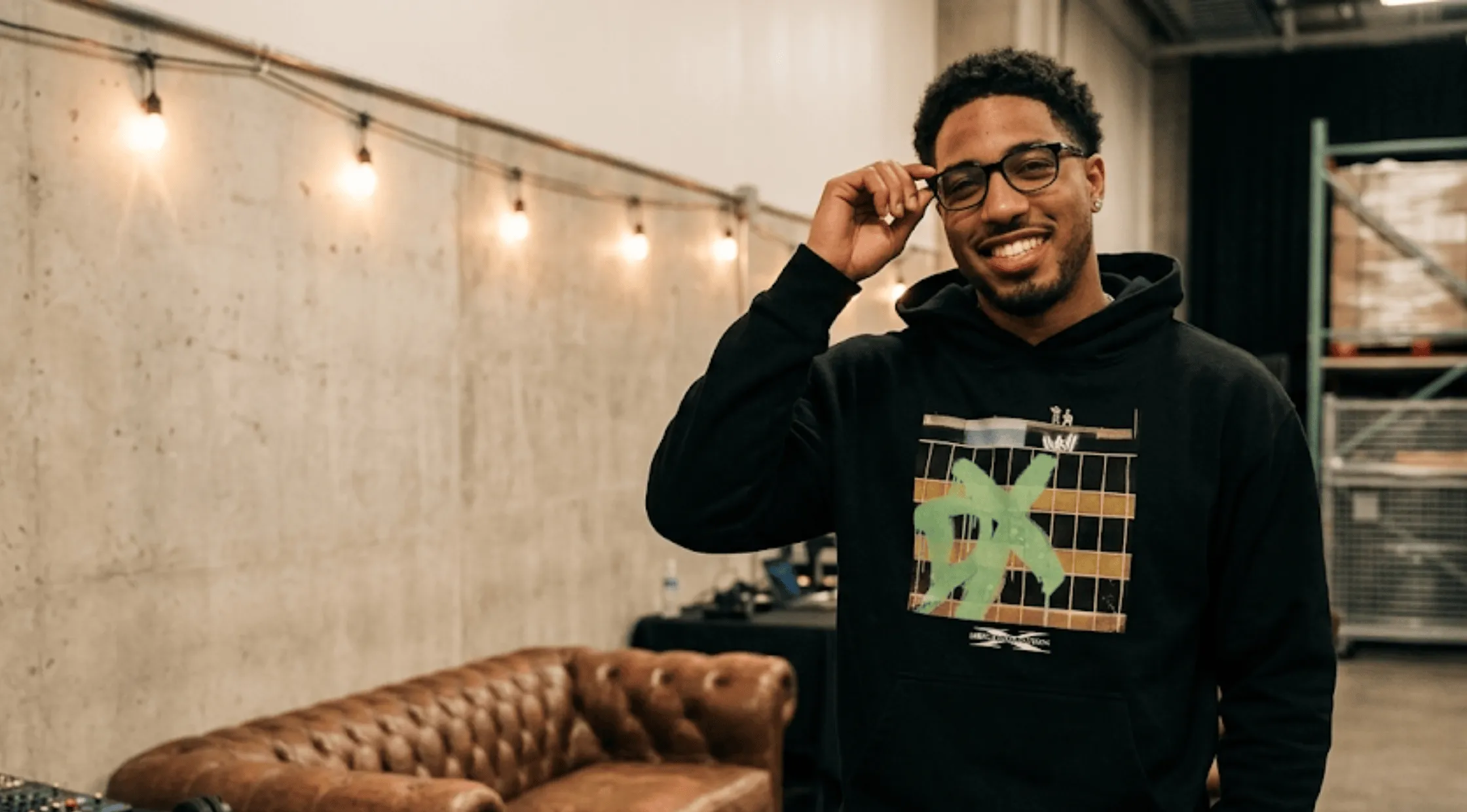 Tyrese Haliburton wearing the Monday Night RAW black pullover hoodie featuring the square grid print, neon green DX spray-paint graphic, and white D-Generation X logo text.