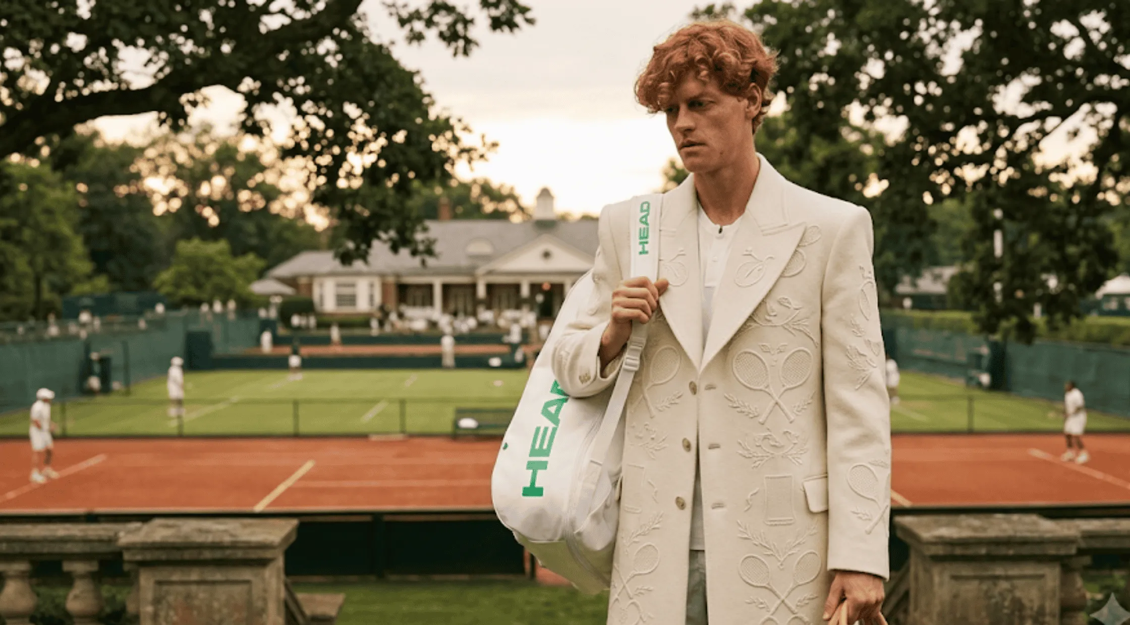 Jannik Sinner wearing a beige floor-length embroidered tennis heritage trench coat with a subtle racket motif at Wimbledon 2026.