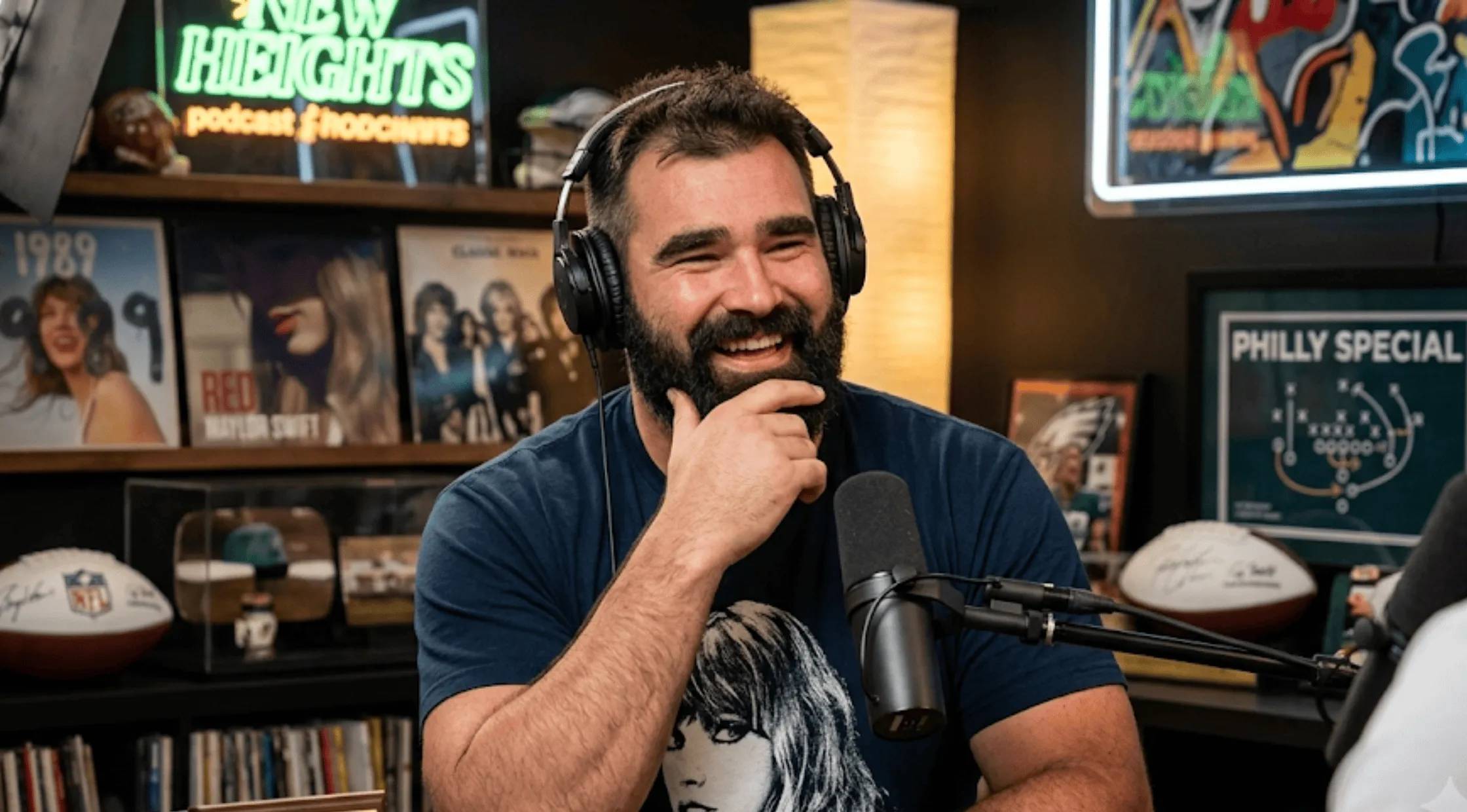 Jason Kelce wearing a navy blue Taylor Swift The Eras Tour Midnights long sleeve t-shirt with a front portrait graphic and sleeve typography.