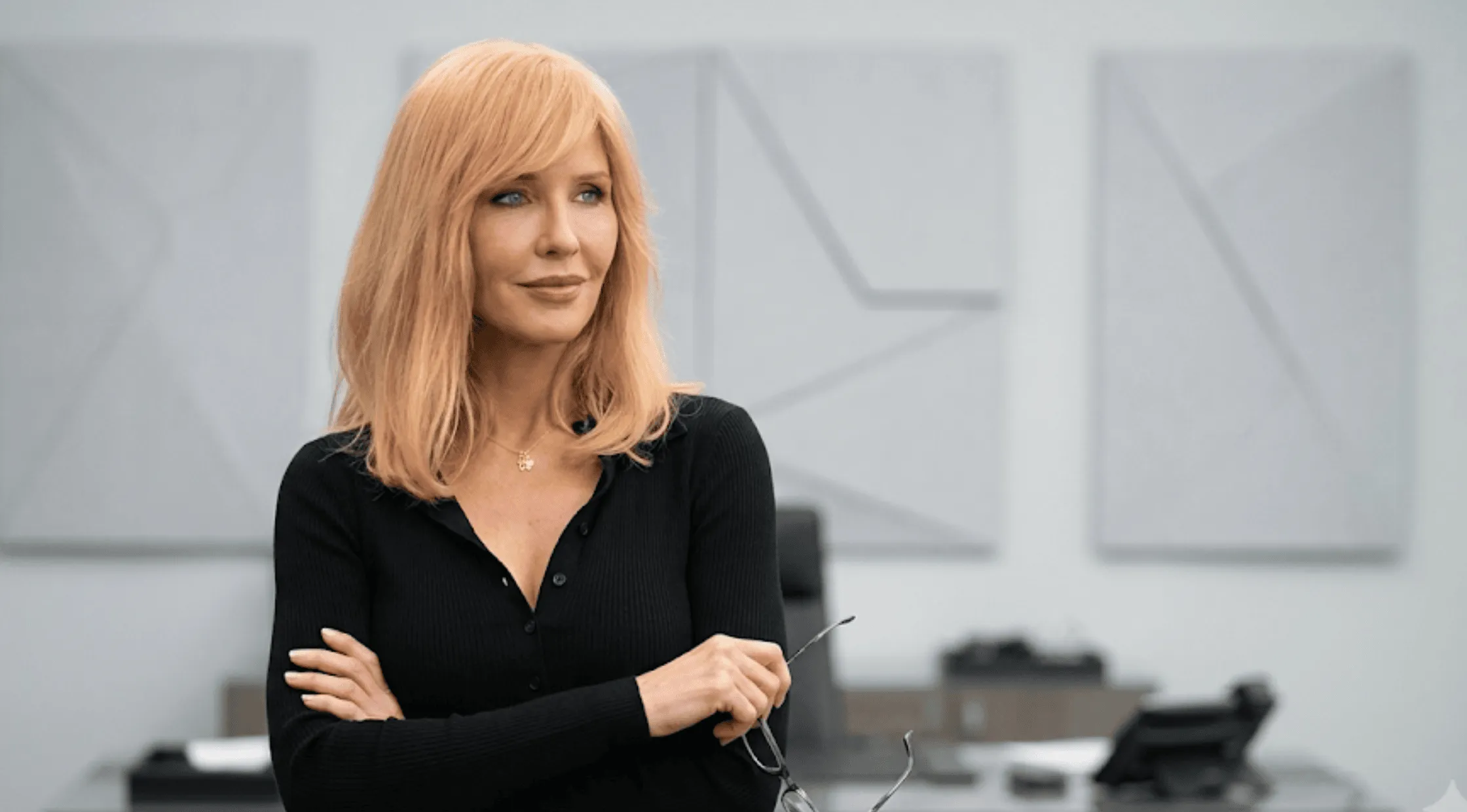 Beth Dutton looking thoughtful, wearing her signature fitted black long-sleeve henley cardigan with a pointed collar and open V-neckline.