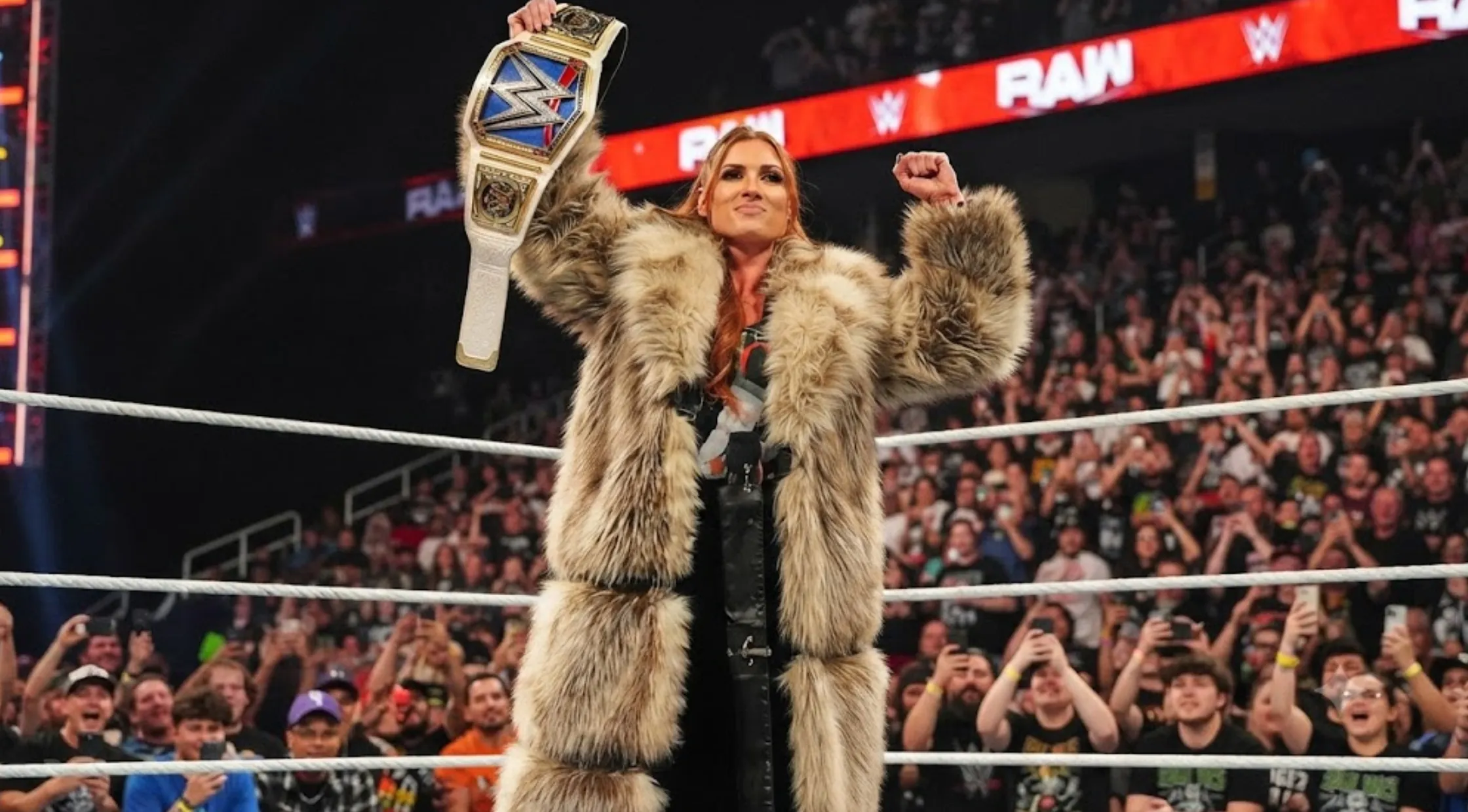 Becky Lynch Monday Night RAW 2026 oversized brown faux fur duster coat with shawl collar and floor-length tiered design