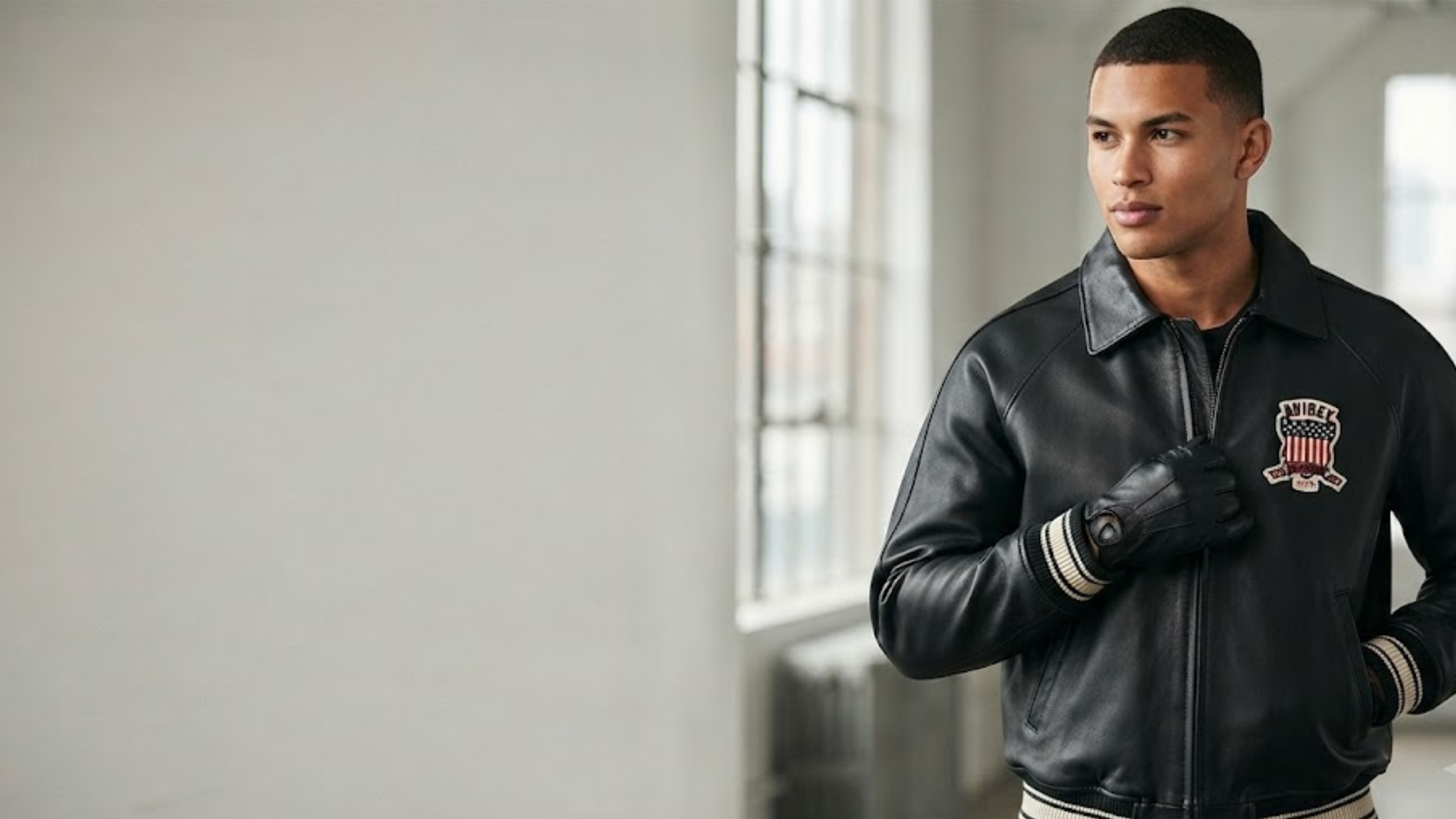 All Americans Avirex Black and Red Leather Bomber Jacket with collegiate patches and striped rib-knit cuffs