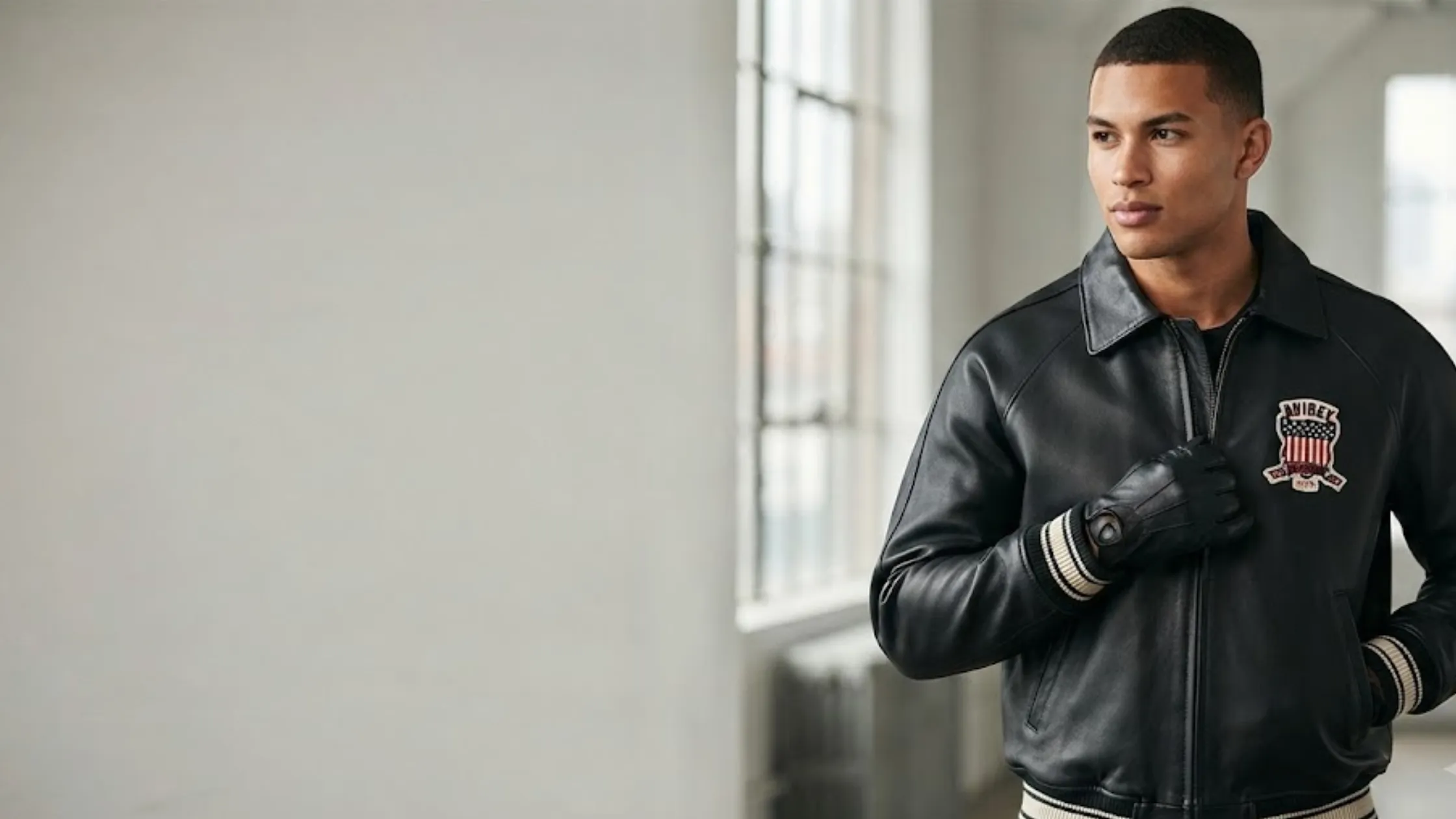 All Americans Avirex Black and Red Leather Bomber Jacket with collegiate patches and striped rib-knit cuffs