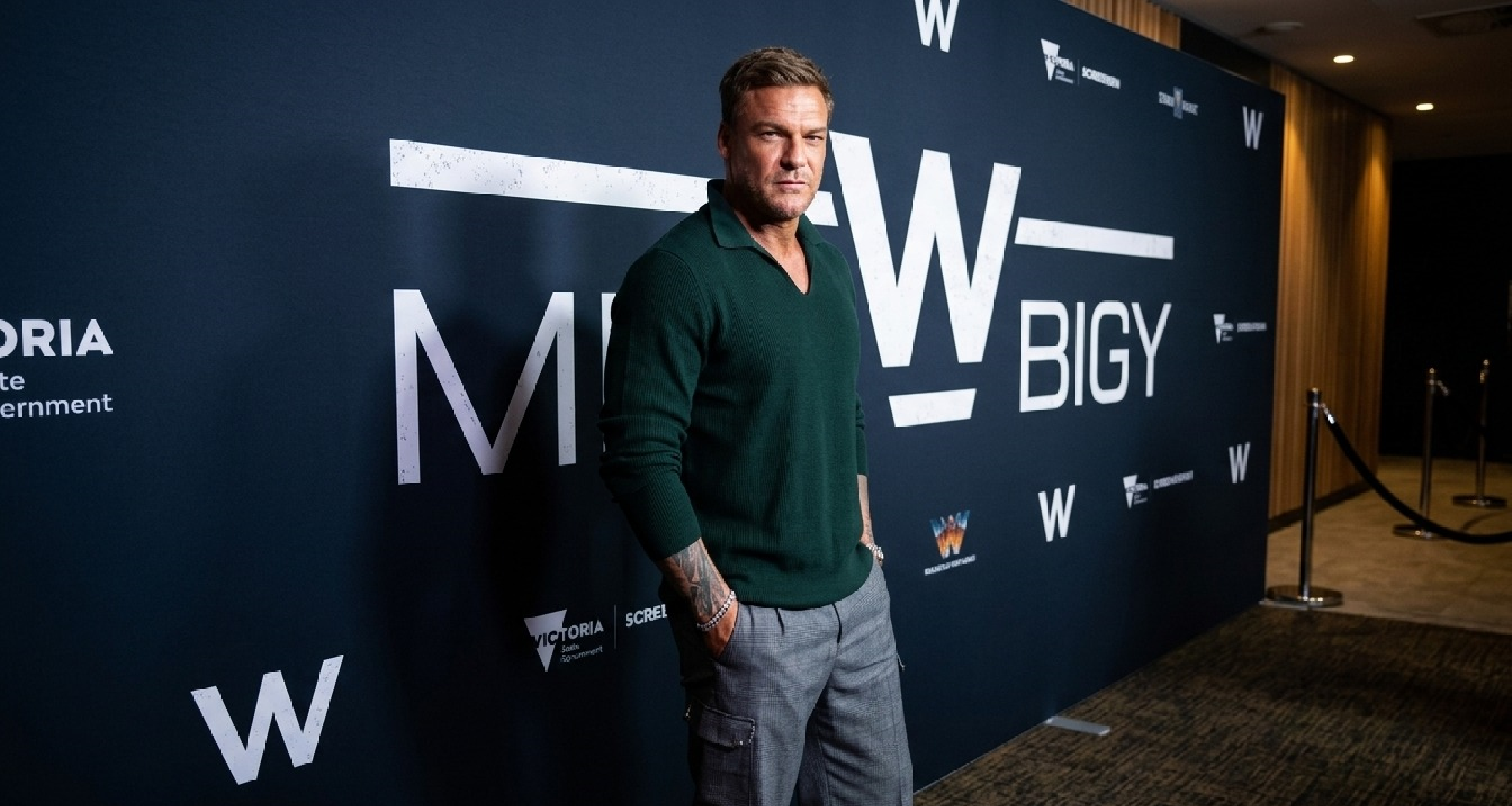 Alan Ritchson War Machine 2026 premiere deep green ribbed Johnny collar sweatshirt modern menswear style