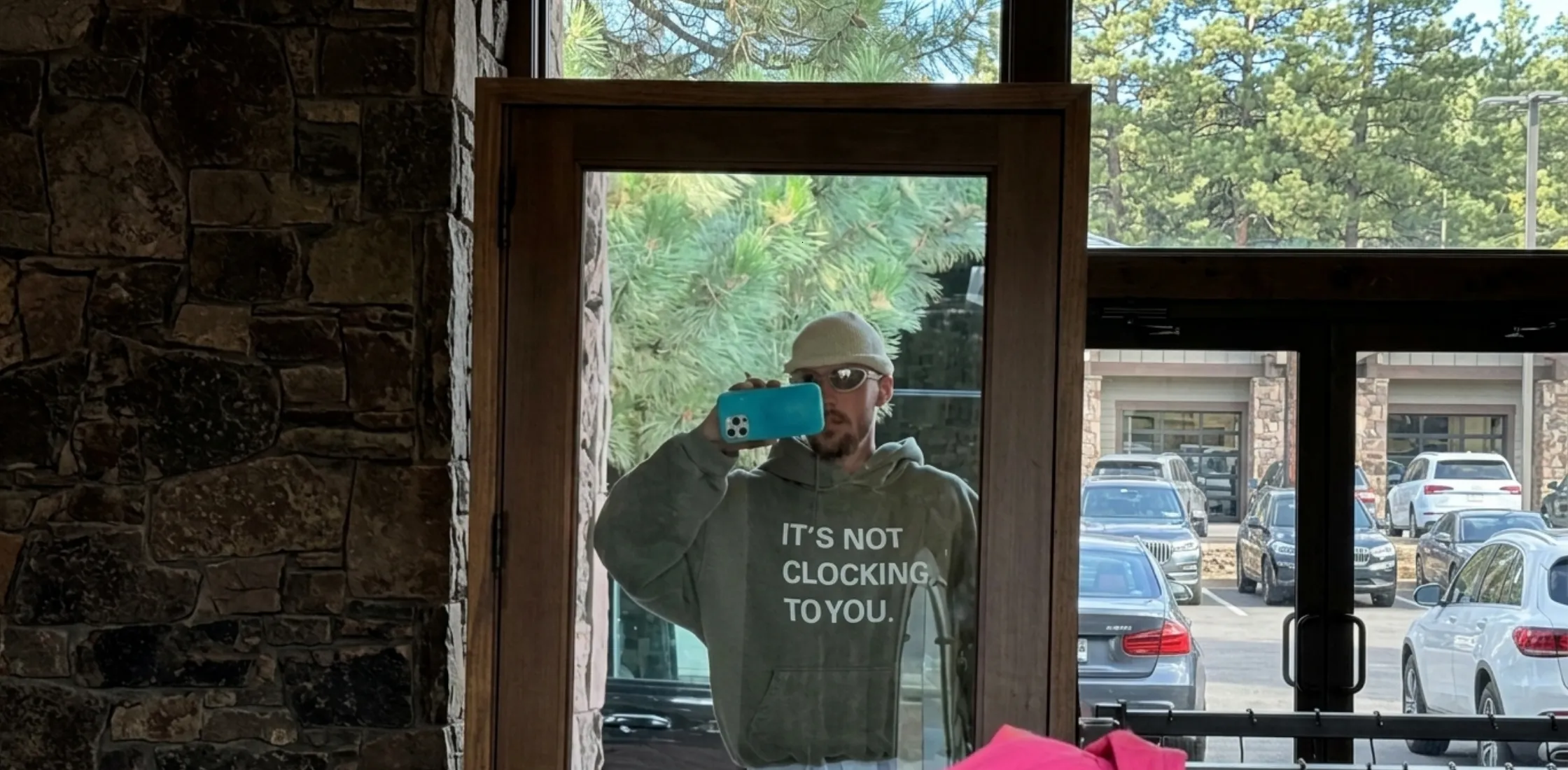 It’s Not Clocking To You olive green hoodie with bold white text graphic front design, oversized streetwear fit, minimal modern pop culture inspired sweatshirt with kangaroo pocket and hood.