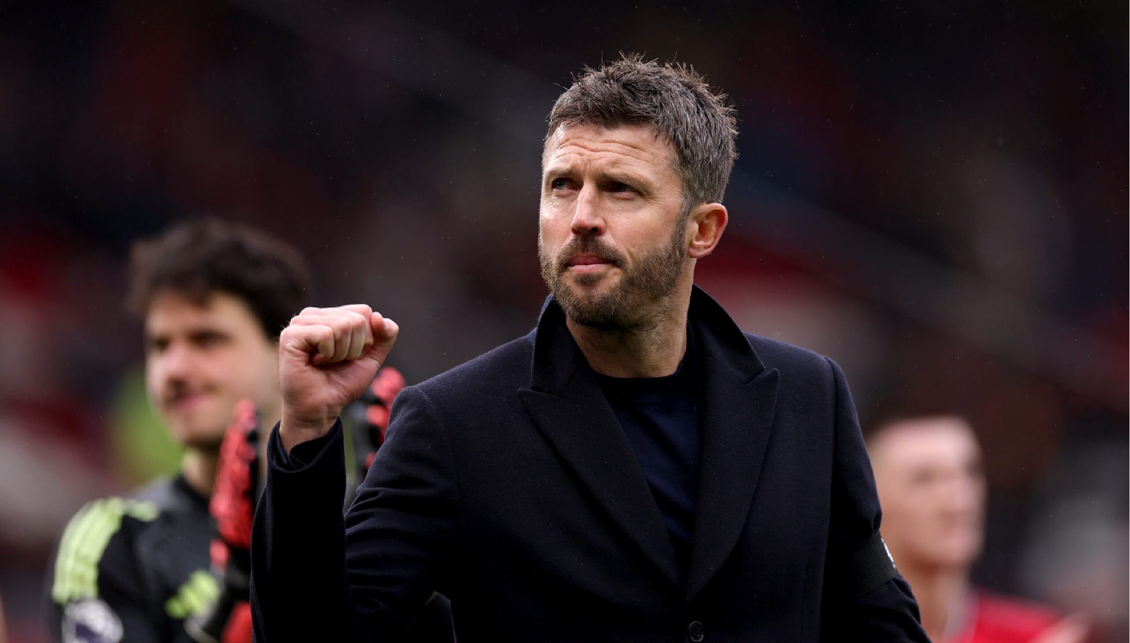 Michael Carrick wearing a mid-thigh black wool blend overcoat during the West Ham United vs Manchester United Premier League match, pointing on the touchline with a commanding presence.