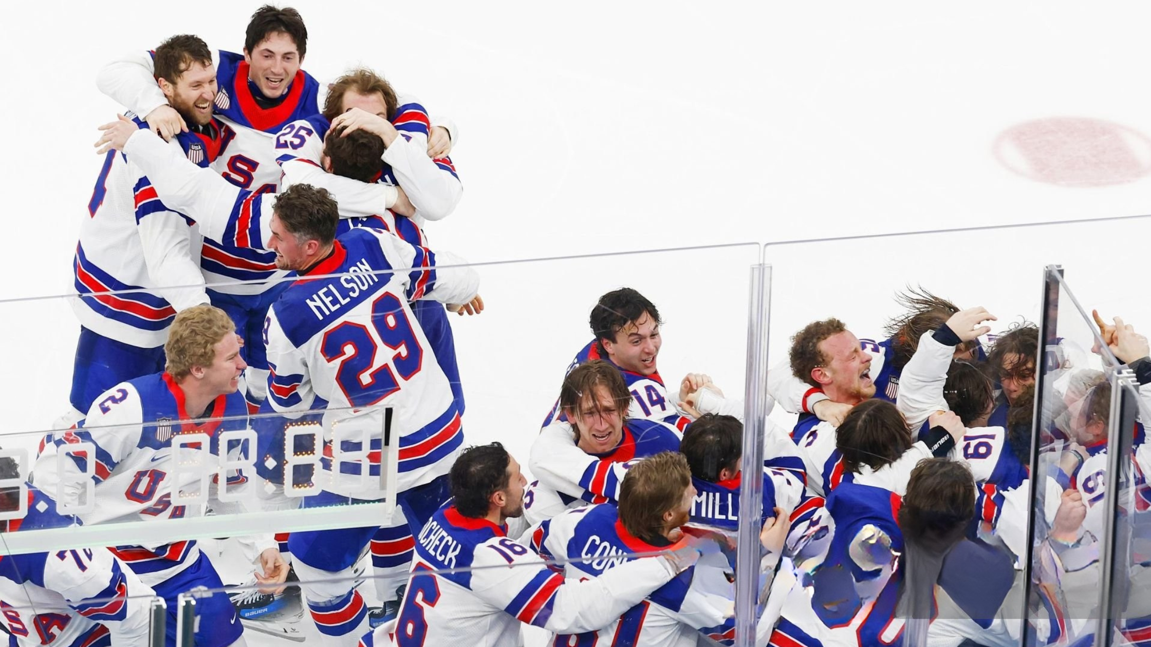 Jack Hughes celebrates after scoring the overtime gold medal goal as Team USA players in red, white, and blue jerseys erupt in victory at the Milan Cortina Olympics 2026 men’s ice hockey final.