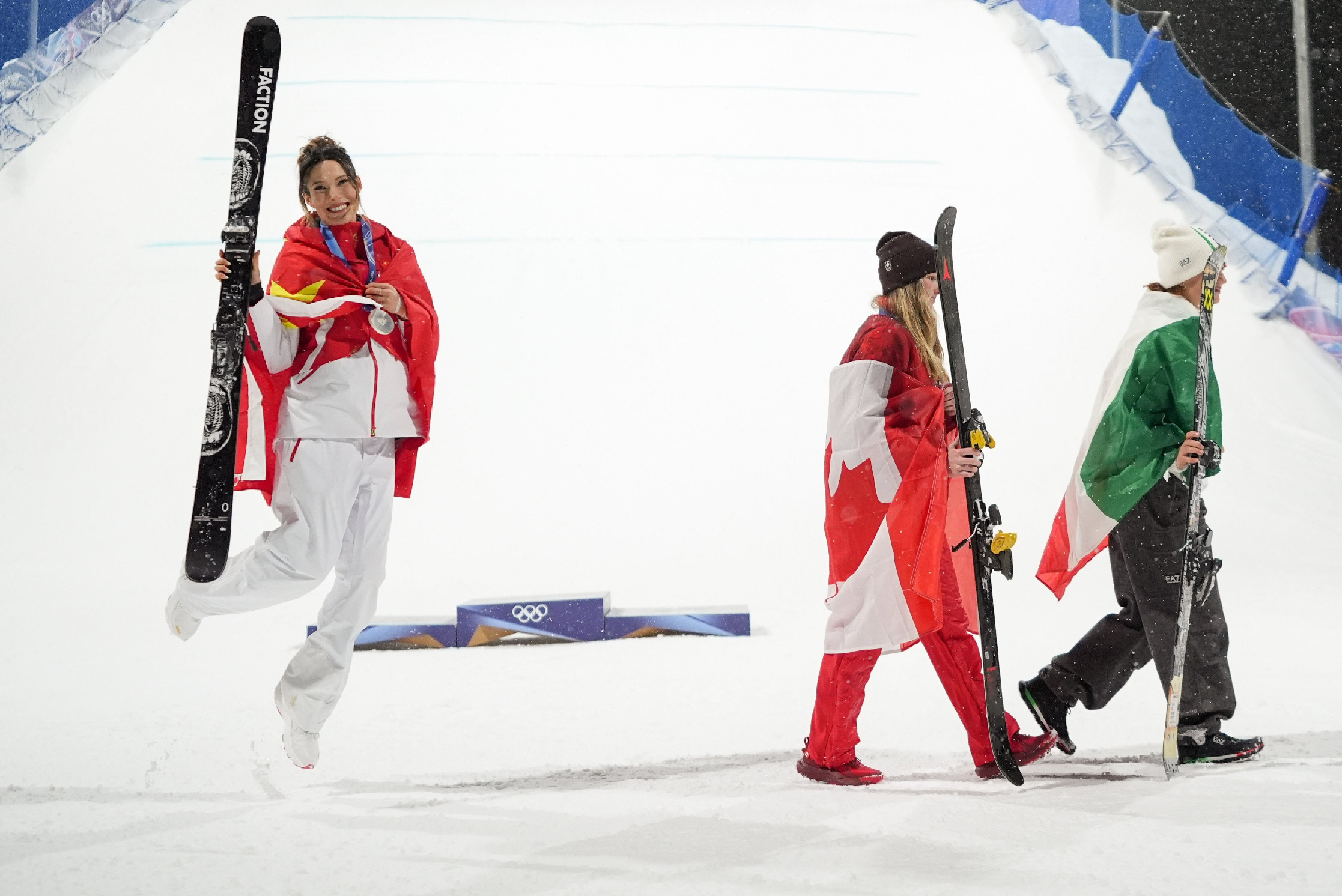 Team China athletes wearing high-tech uniforms at Milano Cortina 2026 Winter Olympics, celebrating gold medals in snowboarding, freestyle skiing, and speedskating