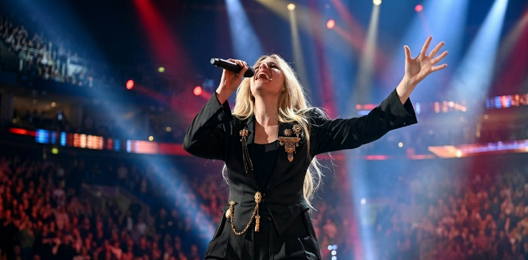 Renee Rapp performing at iHeartRadio Z100’s Jingle Ball 2025 in black tail coat with gold accents