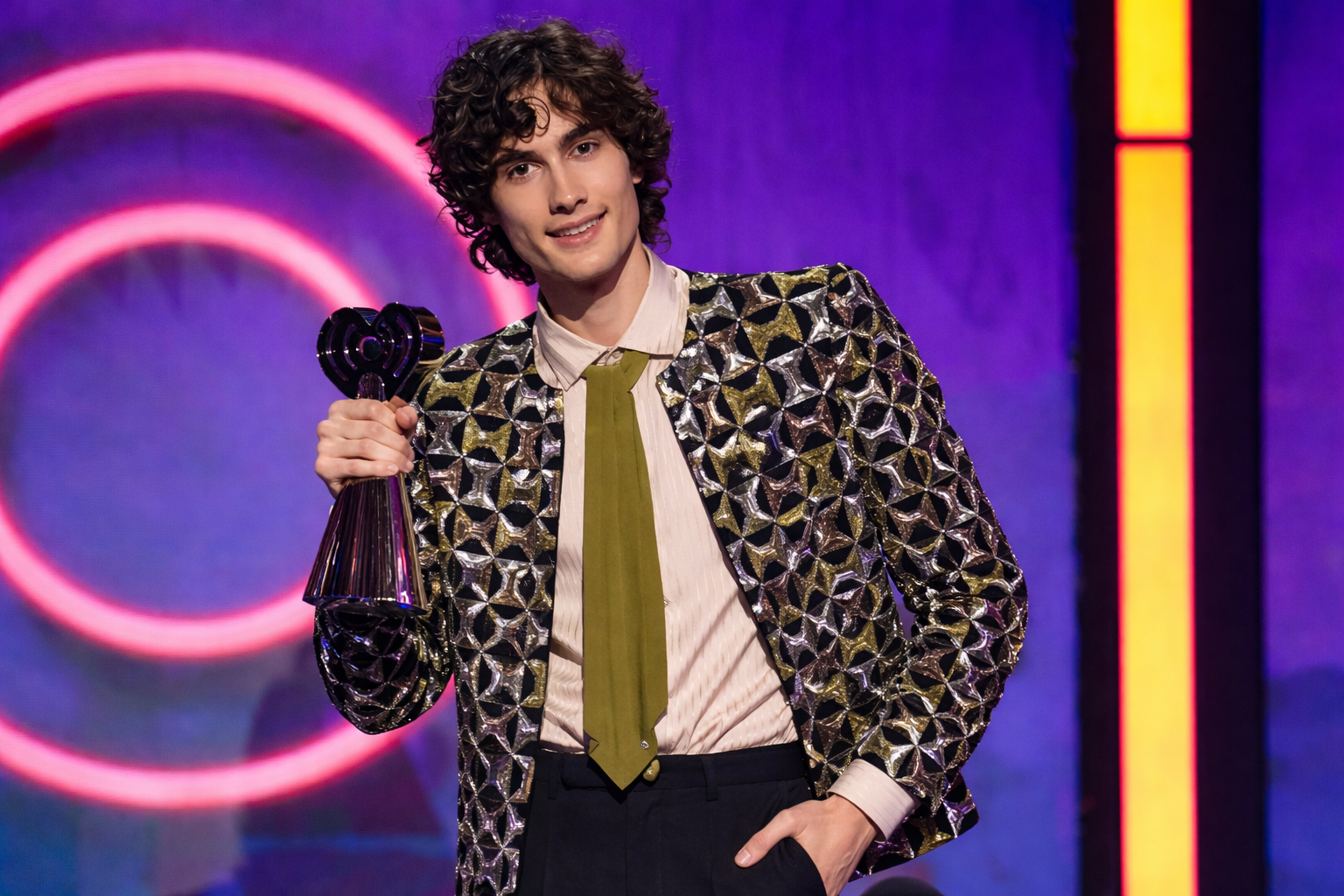 Sombr 2026 iHeartRadio Music Awards black open-front metallic sequin bolero jacket with geometric collarless design