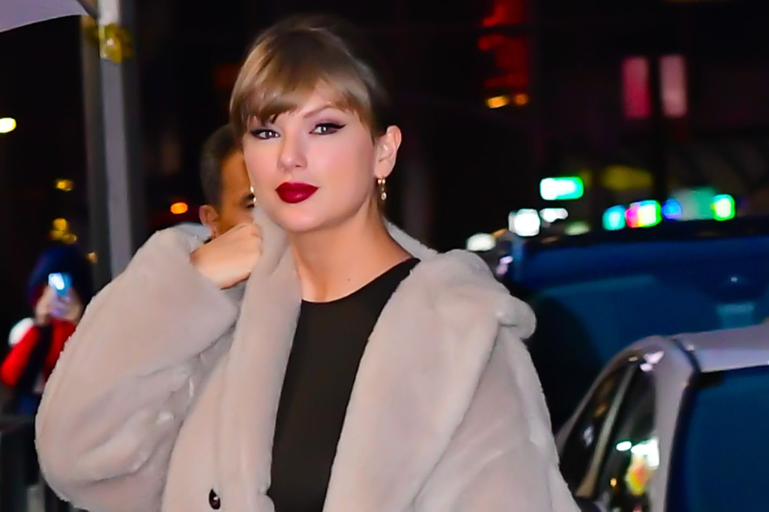 Taylor Swift wearing a neutral plush oversized coat outside The Late Show with Stephen Colbert in New York City on December 10, 2025