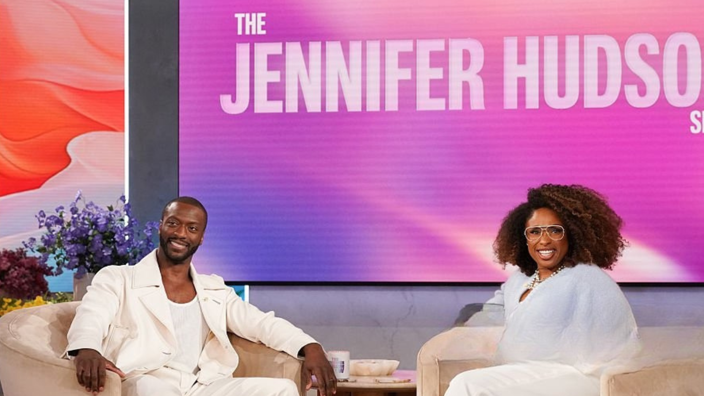 Jennifer Hudson and Aldis Hodge on the set of "The Jennifer Hudson Show," February 23, 2026, wearing stylish outfits that blend chic minimalism with vibrant colors.